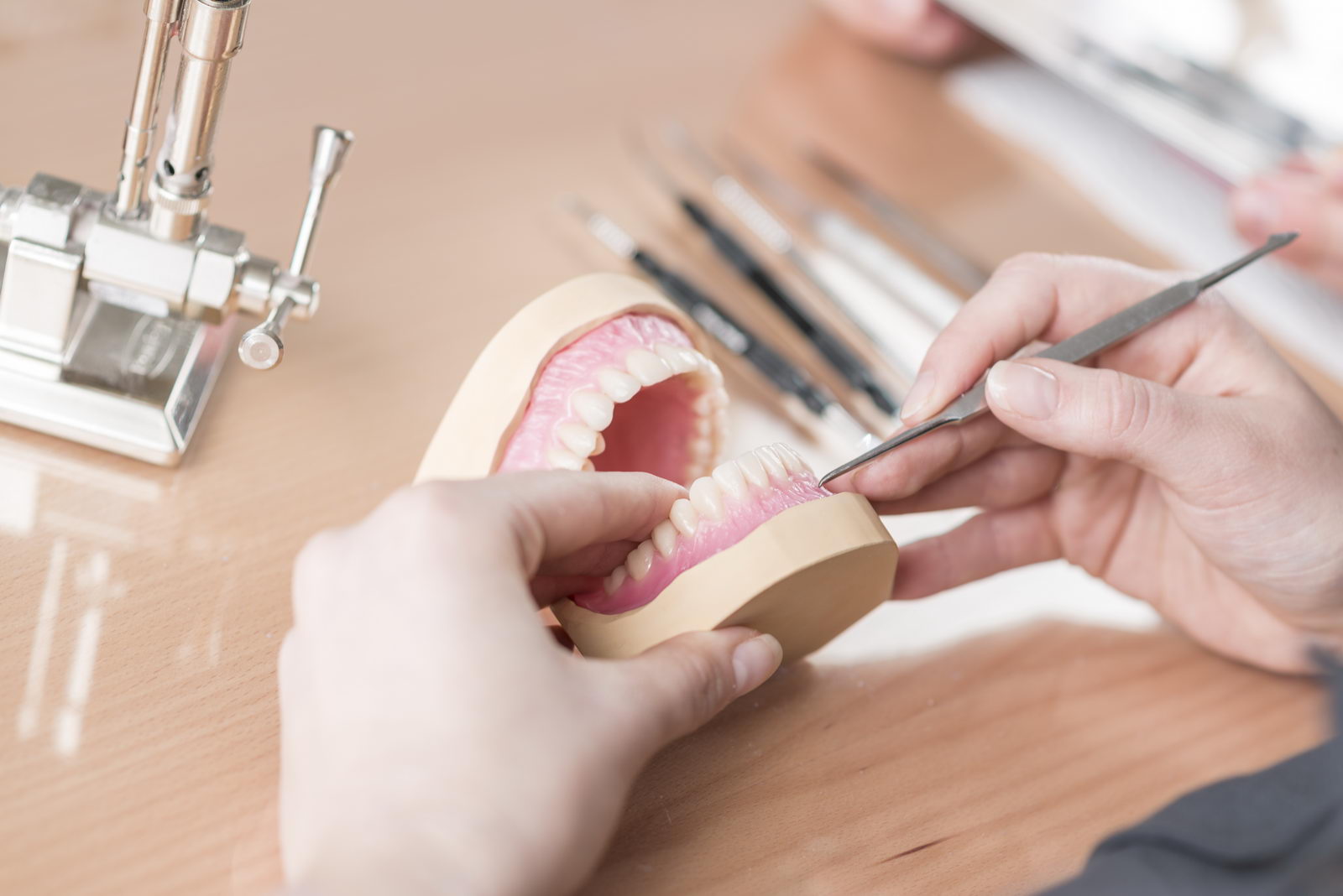 Feinarbeit ist Handarbeit an der Zahn-Prothese.Zahntechnikerin an ihrem Arbeitsplatz.