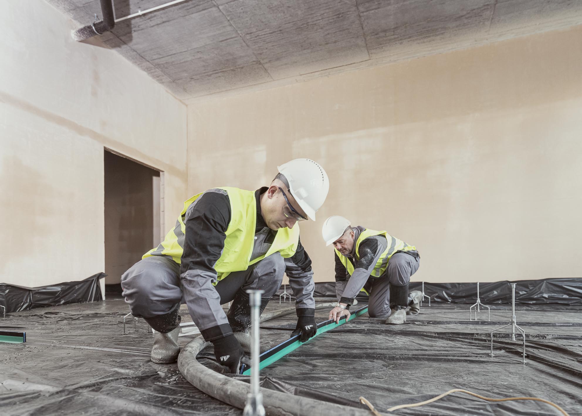 Betonboden legen, mit fliesenden Beton. Baustelle mit Arbeitern in der Vorbereitung.