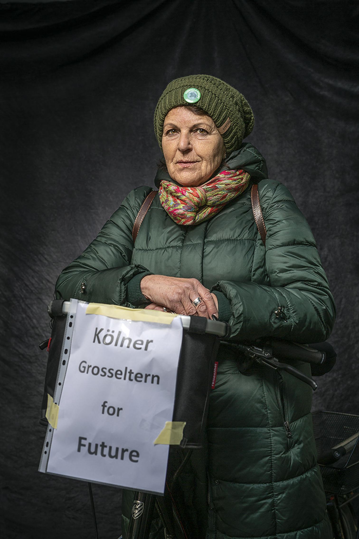 Frau mit Schild von Kölner Großeltern for Furure, vor Studiohintergrund auf einer FfF Demo in Köln