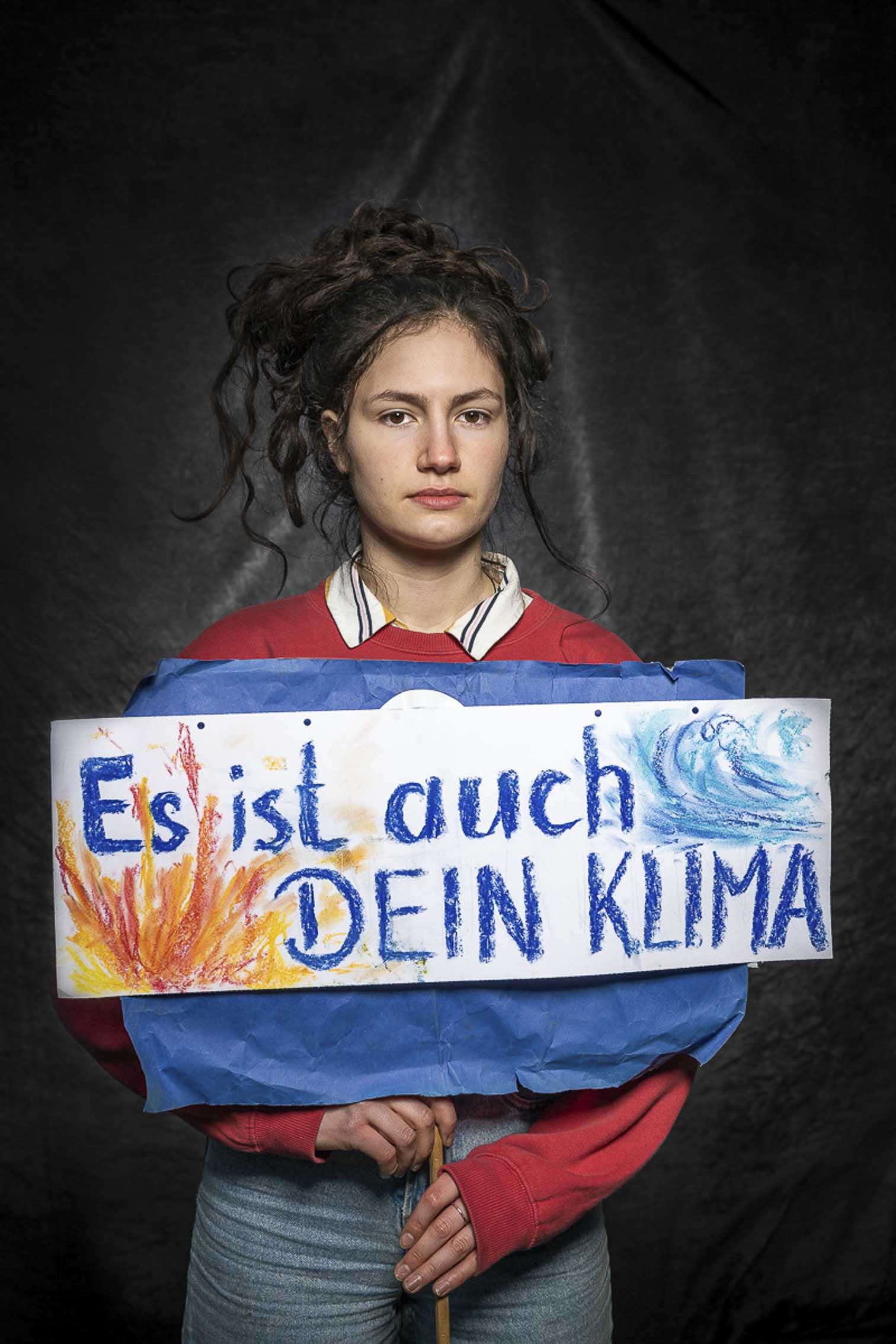 Schülerin mit Schild: Es ist auch dein Klima. Vor Studiohintergrund auf einer FfF Demo in Köln